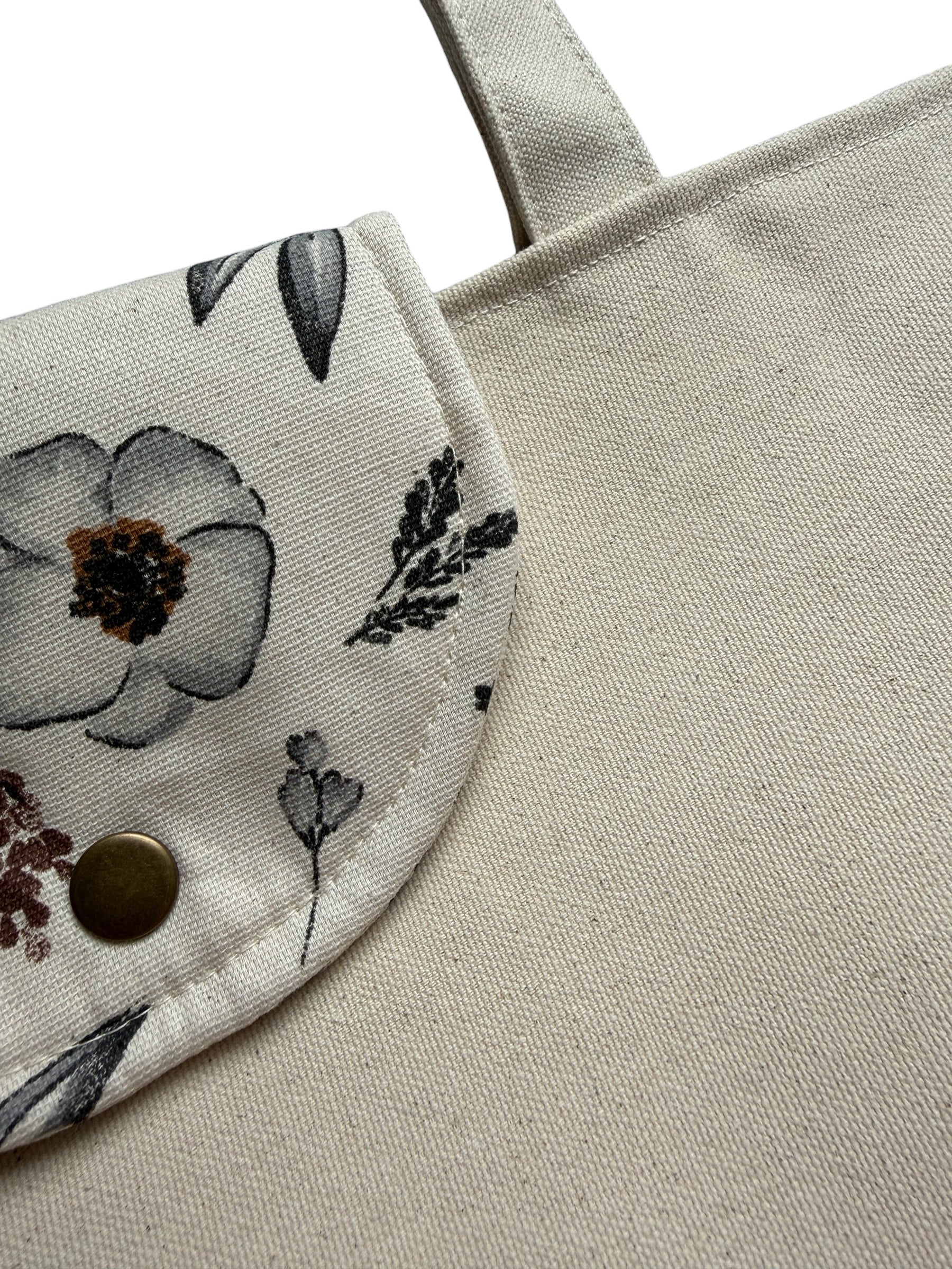 Close-up of a beige tote bag with floral patterned tag