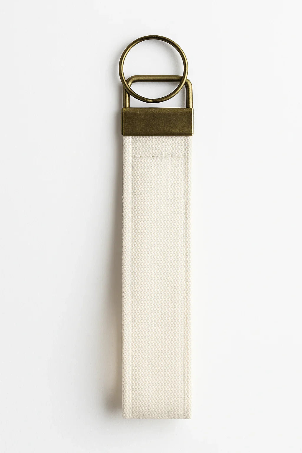 Minimalist canvas wristlet keychain with brass ring and neutral strap on white background