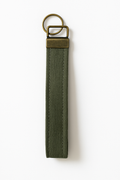Olive green canvas wristlet keychain with brass hardware on white background