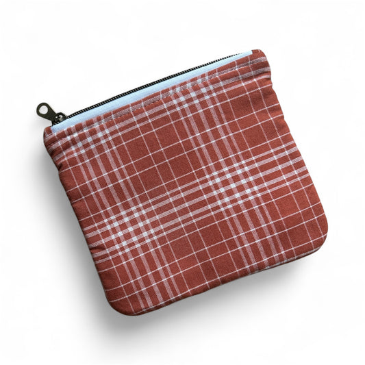 Minimalist canvas pouch with red and white plaid pattern and black zipper on white background