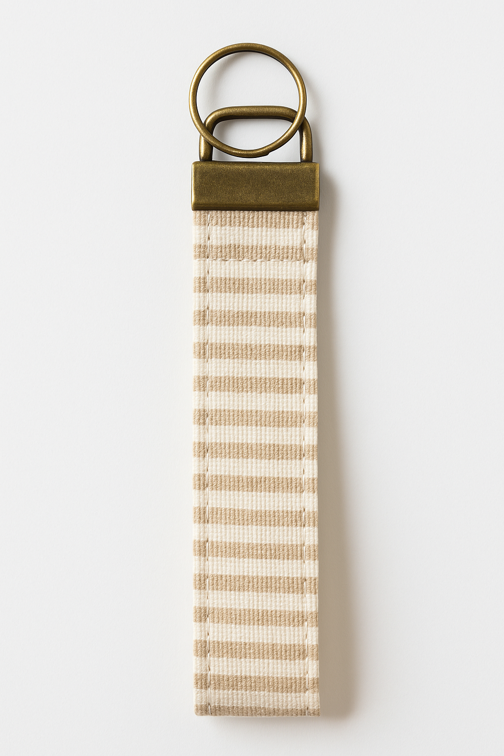 Neutral striped canvas wristlet keychain with brass hardware on white background