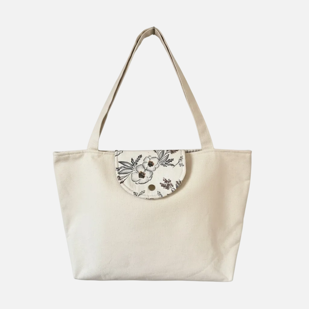 Beige tote bag with floral flap on a white background